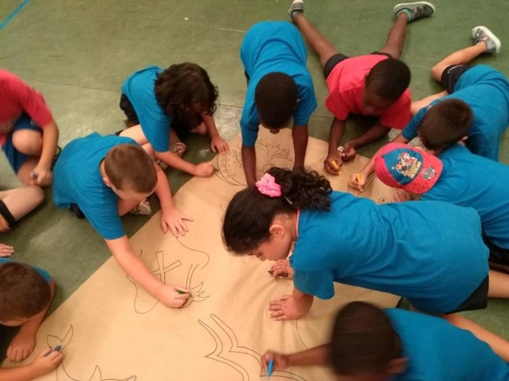 Algunos niños hacen un mural en las colonias urbanas de Cruz Roja