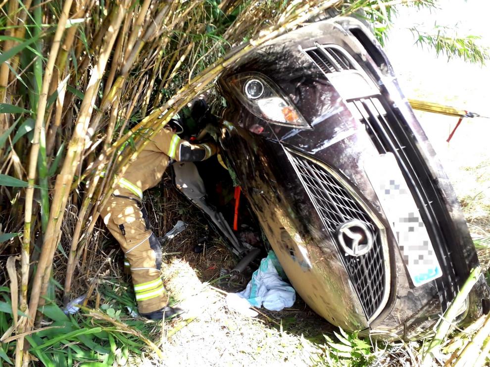 Un bombero de la Diputación de Zaragoza, junto al turismo siniestrado.