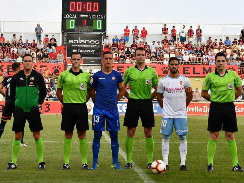 El árbitro López Toca, cántabro, en el centro de la imagen antes del Reus-Real Zaragoza del año pasado, el segundo y último partido que ha dirigido a los zaragocistas desde su aparición en Segunda División hace tres campañas.Badía, portero del Reus, y Javi Ros, del Zaragoza, posan a su lado junto con el resto del equipo arbitral.