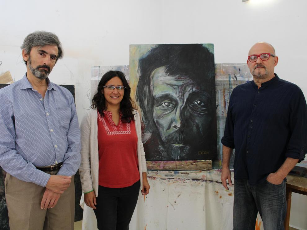 Dos integrantes de Pierres junto al cuadro donado y el artista Fernando Escribano a la derecha.