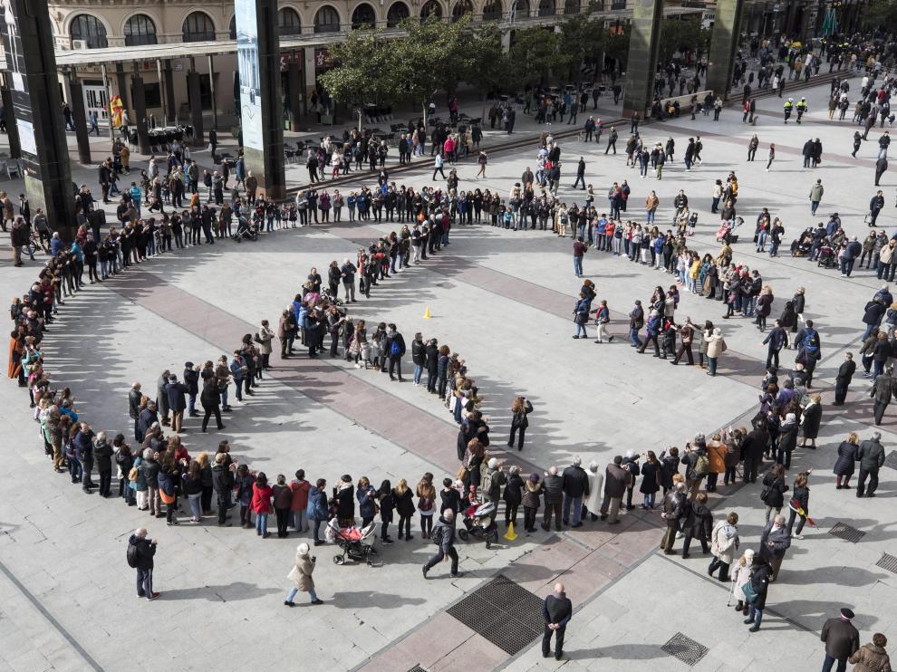 Un grupo de personas forma el símbolo de la paz en la plaza del pilar de Zaragoza, durante la celebración del Día de la Paz de 2019.