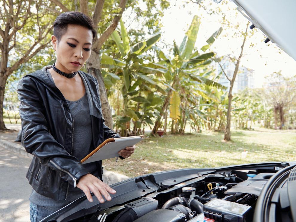 Una mujer siguiendo el manual de un coche.