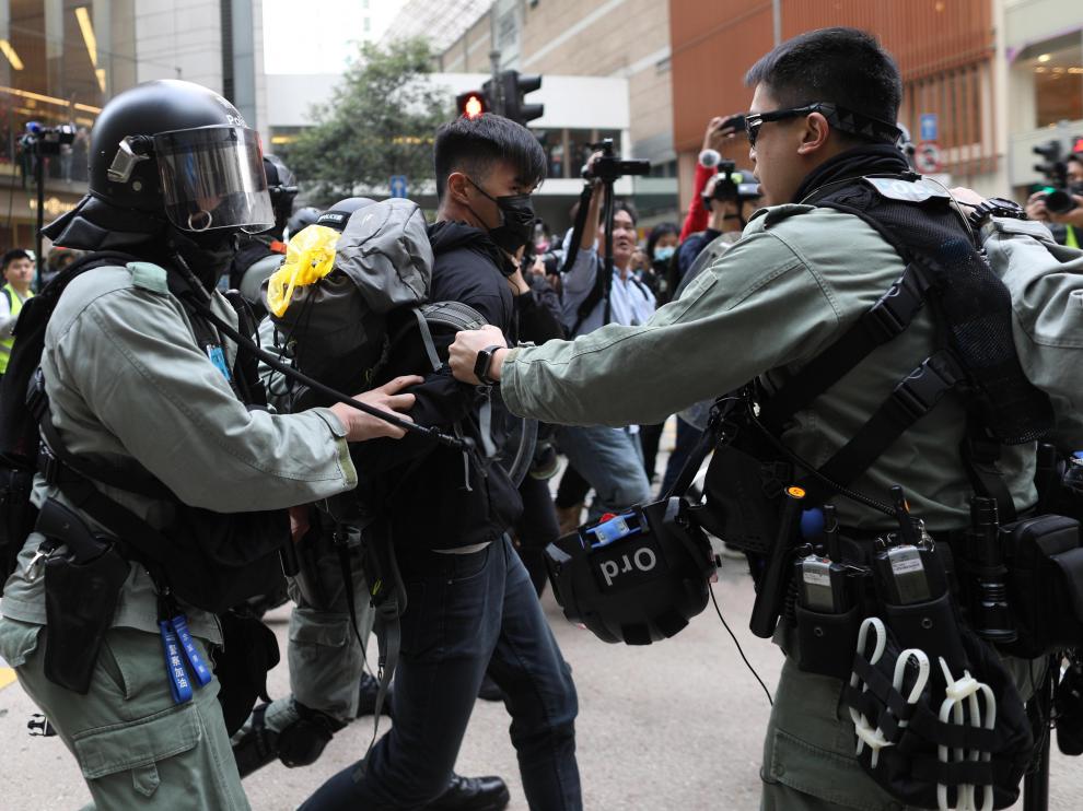 Dos policías retienen a uno de los manifestantes este domingo en las calles de Hong Kong.