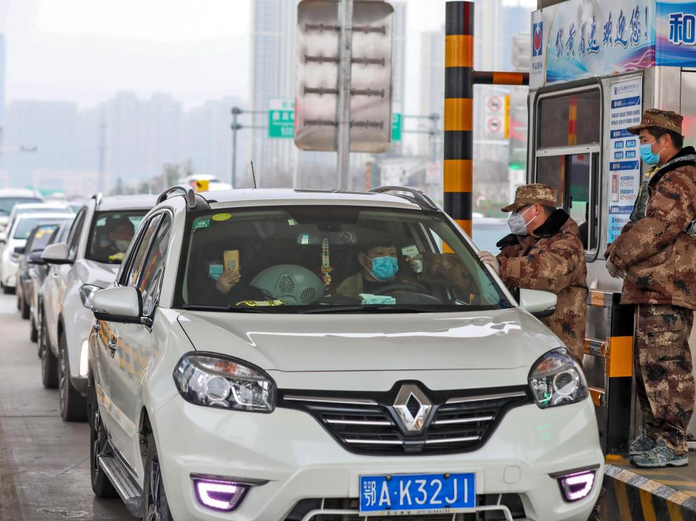 Un militar comprueba la temperatura de dos personas en un coche en Wuhan.