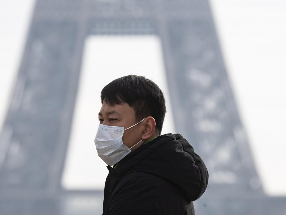 Un hombre con mascarilla, delante de la torre Eiffel.