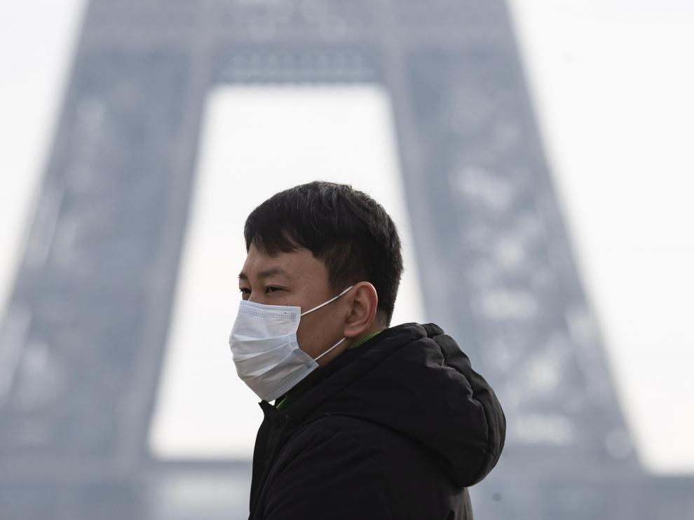 Un hombre con mascarilla, delante de la torre Eiffel.