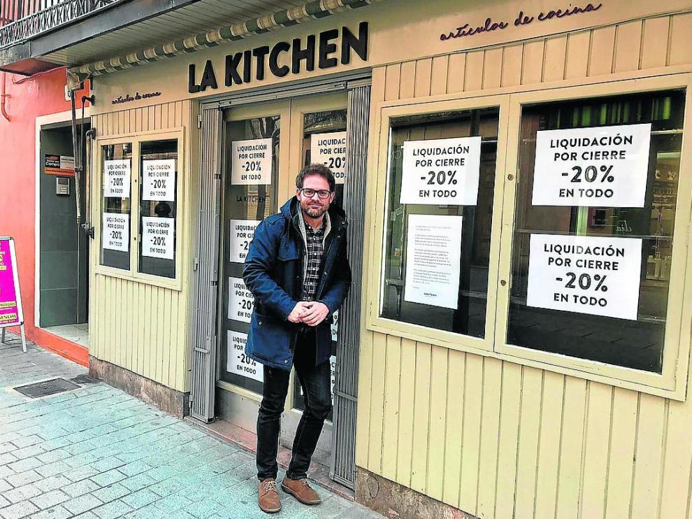 Jorge Álvarez, frente a su tienda en el Coso de Huesca, empapelada de papeles de cierre.