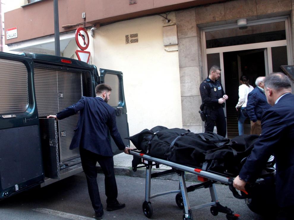 Dos personas trasladan el cadáver de una mujer de 41 años, hallado este lunes por la Policía Local de Gijón con evidentes signos de violencia en su domicilio