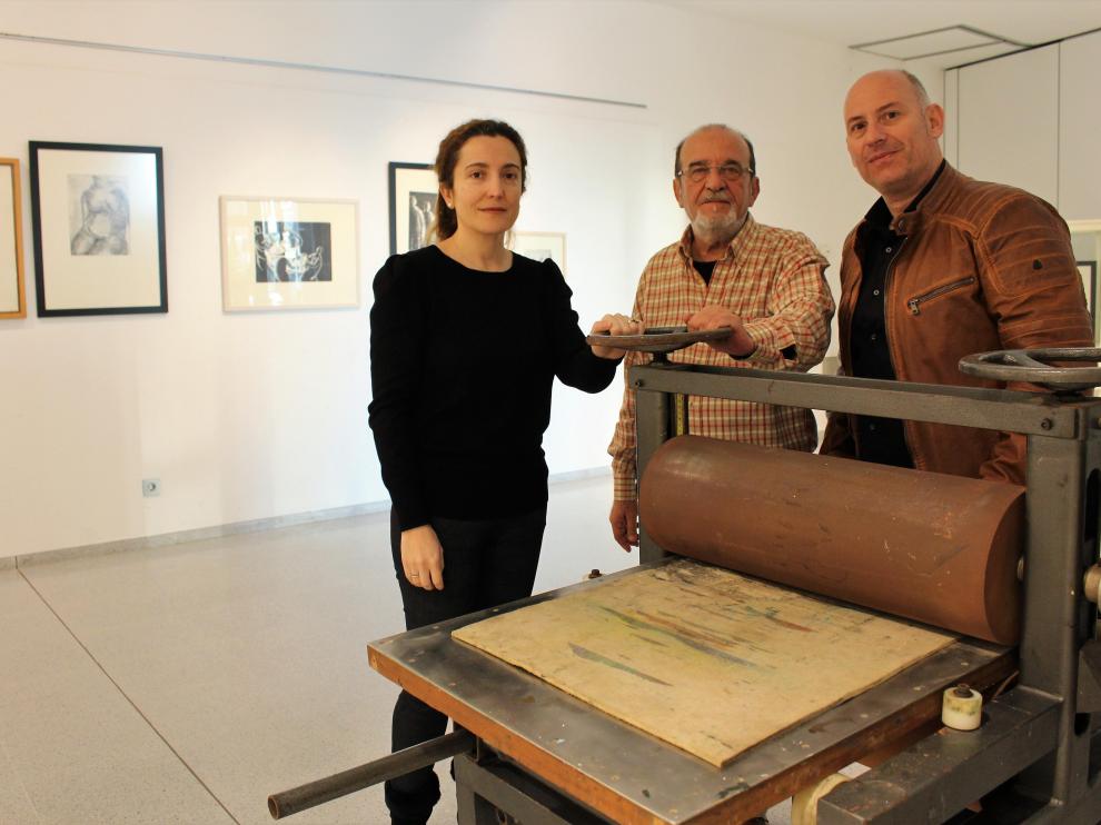 Juan Carlos García (d), Carlos Mas y Laura Baquero, técnico de Cultura del Ayuntamiento de Binéfar, con el tórculo que utilizaba Katia Acín.