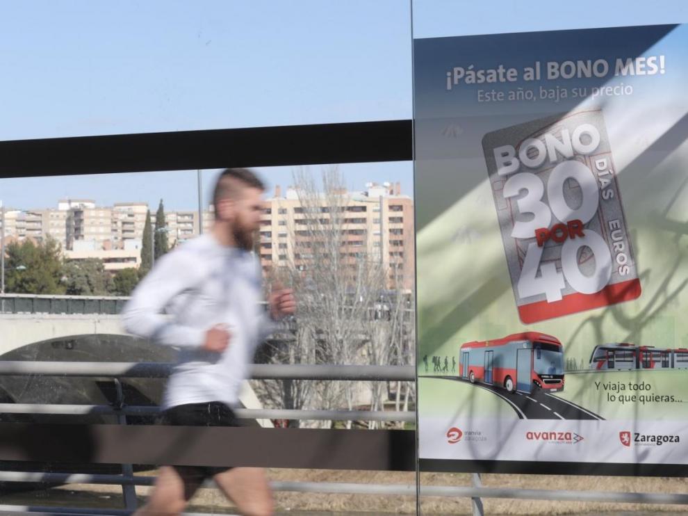 Un hombre pasa corriendo por delante de una marquesina de bus con el anuncio de 30x40.