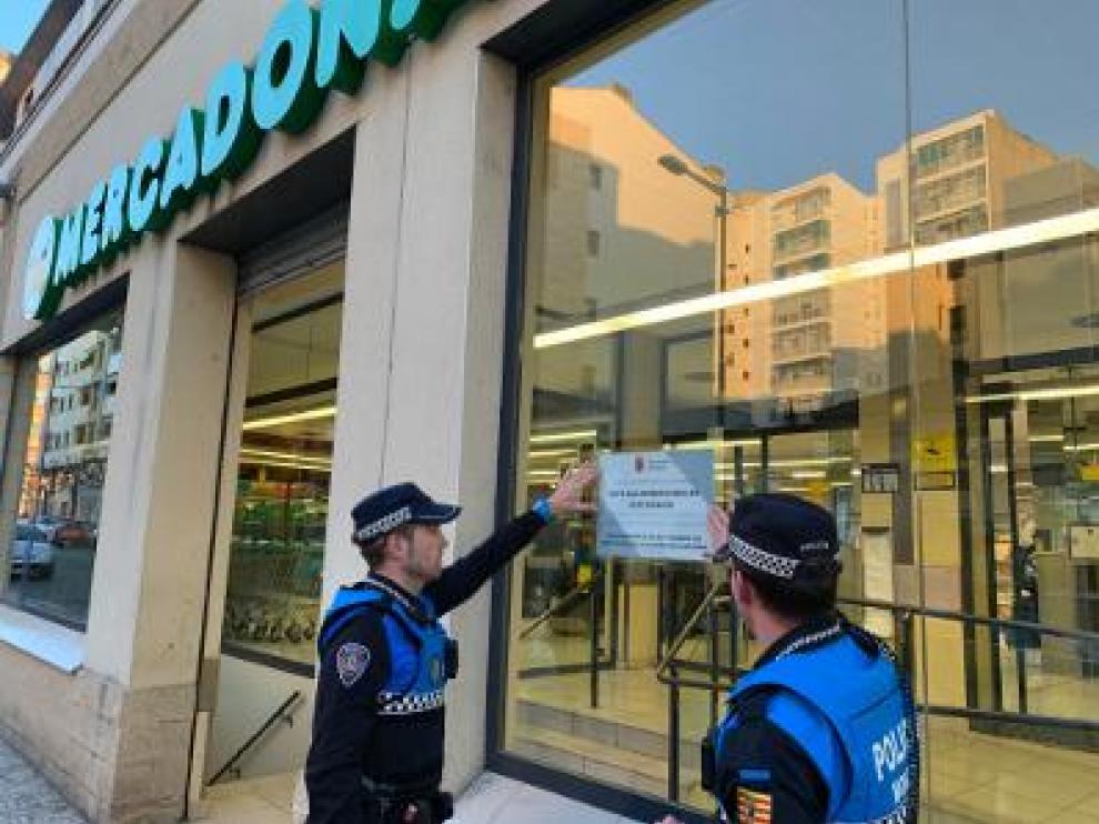 Agentes de policía colocan un cartel en un supermercado