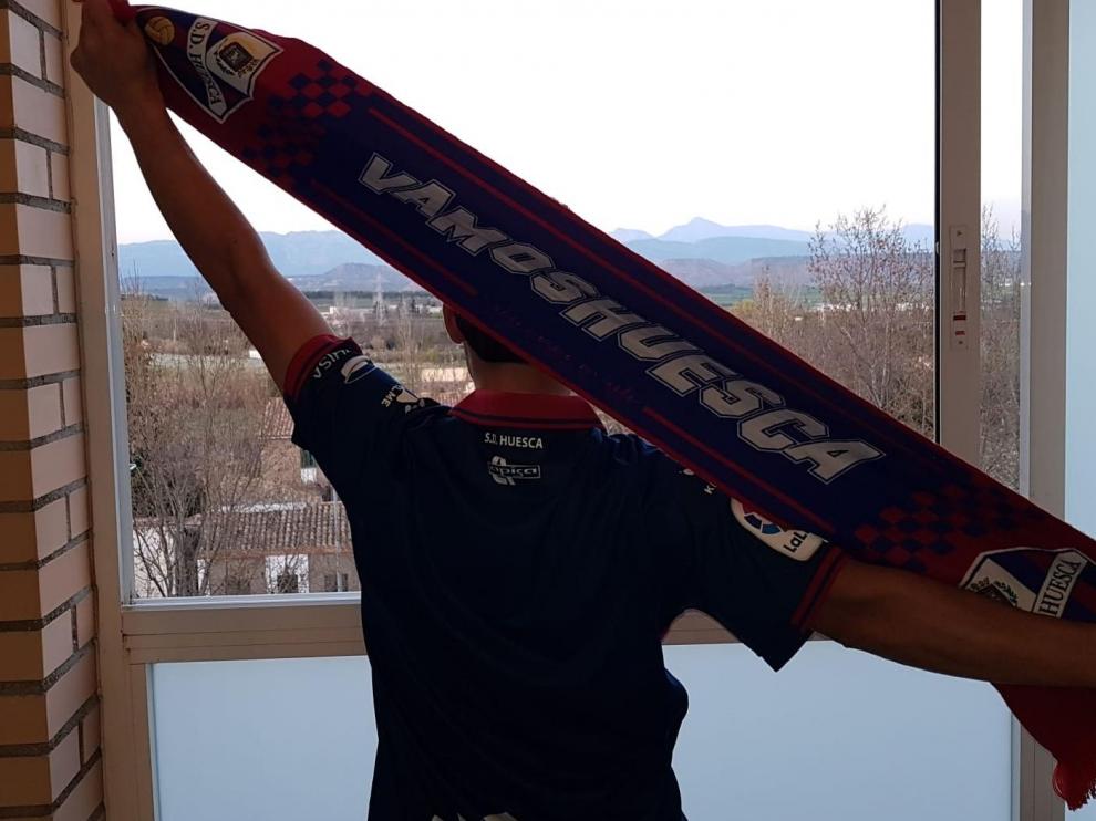 Un aficionado de la SD Huesca se asoma a su ventana para cantar el himno.