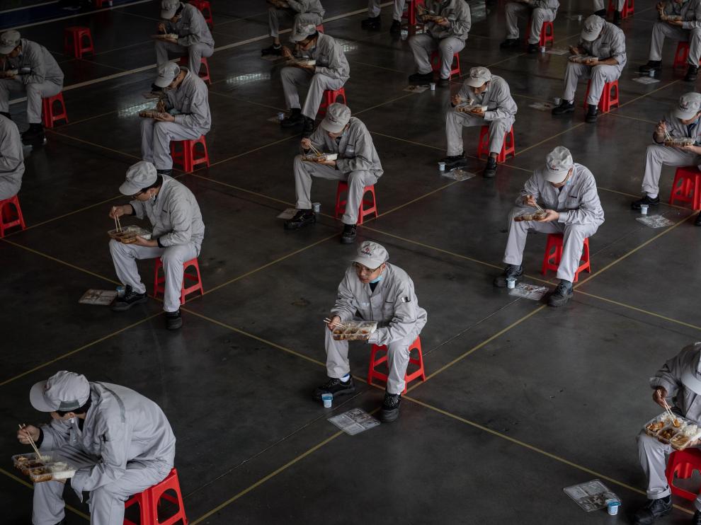 Trabajadores chinos comen en asientos habilitados y colocados para mantener la distancia prudencial recomendada en la fábrica Dongfeng Honda en Wuhan.