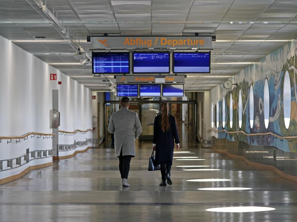 Dos personas caminan por una desierta terminal del aeropuerto de Stuttgart.