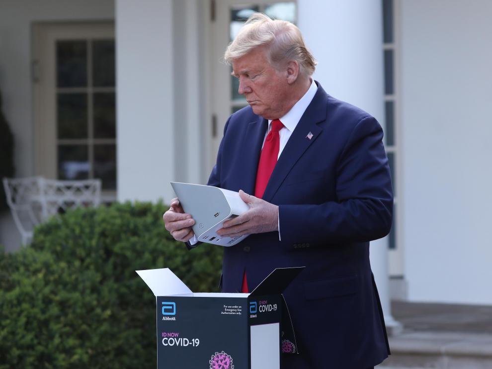 Trump abre una caja de un aparato para realizar test del coronavirus.