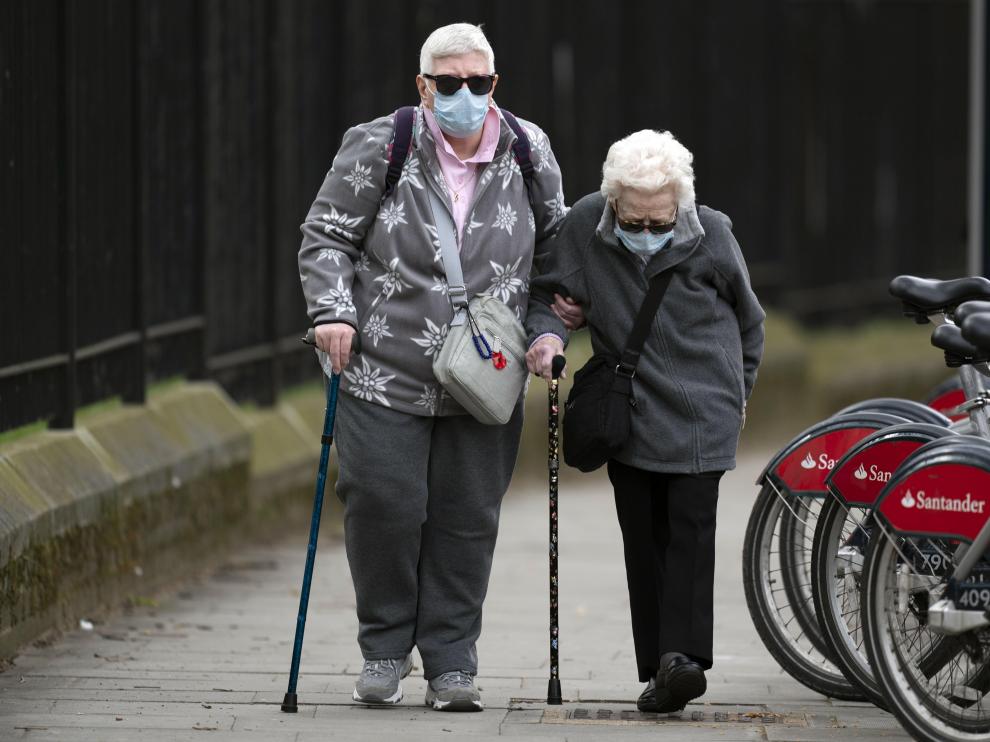Dos mujeres con mascarillas caminan al lado de un hospital de Londres.