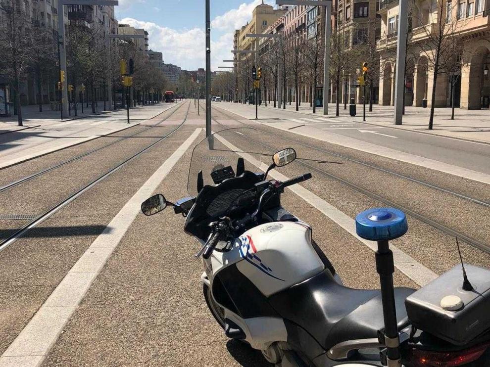 Moto de una patrulla de la Policía Local en un paseo de la Independencia, vacío en Zaragpza