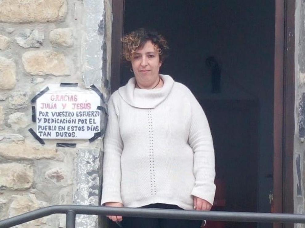 Julia Casajús, en la puerta de su tienda y junto al cartel de agradecimiento colocado por sus vecinos.