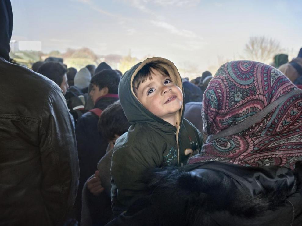 Un niño sirio refugiado sonríe en brazos de su madre en la frontera entre Eslovenia y Austria en noviembre de 2015 Foto: Gervasio Sánchez