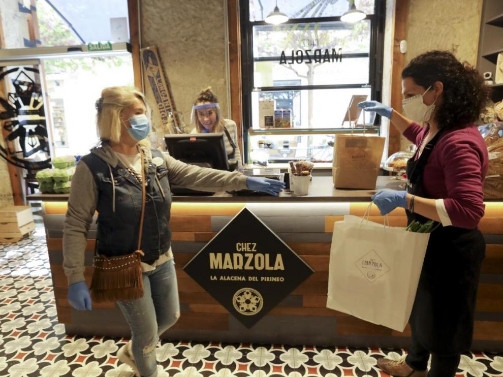 Una voluntaria de la AECC recoge un pedido a domicilio en la tienda de Chez Marzola, de Elena Bernad.