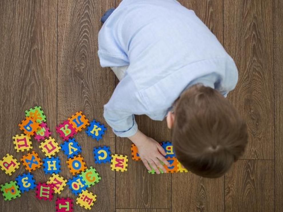 Un niño jugando con unas piezas con letras y símbolos del alfabeto.