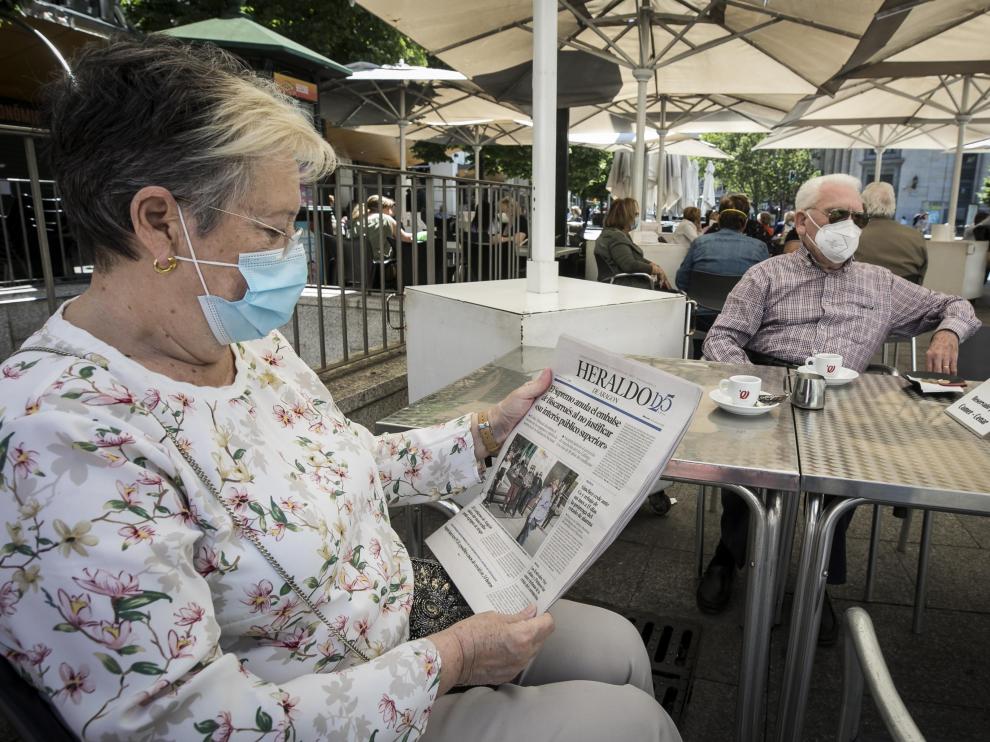 Una pareja lee la prensa mientras toma un café, en una terraza de Zaragoza