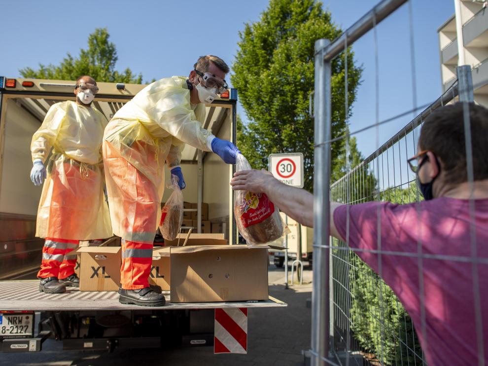 Voluntarios de Cruz Roja entregan pan en una de las casas de los trabajadores del grupo cárnico Toennies puestas en cuarentena por el brote de coronavirus en la planta de Renania.