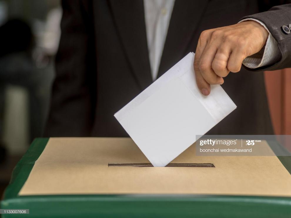 Hand of a person casting a vote into the ballot box during election