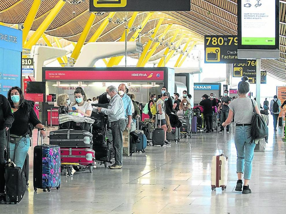 Viajeros esperando para facturar sus maletas en el aeropuerto de Barajas, en Madrid.