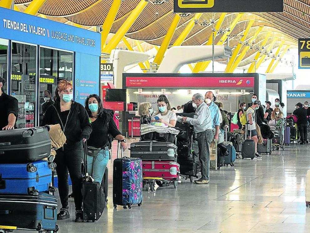 Viajeros esperando para facturar sus maletas en el aeropuerto de Barajas, en Madrid.