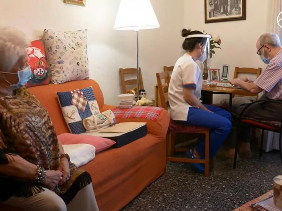 Mercedes Alcázar, en su casa, con marido Paco atendido por una trabajadora del Centro Alzheimer Huesca.