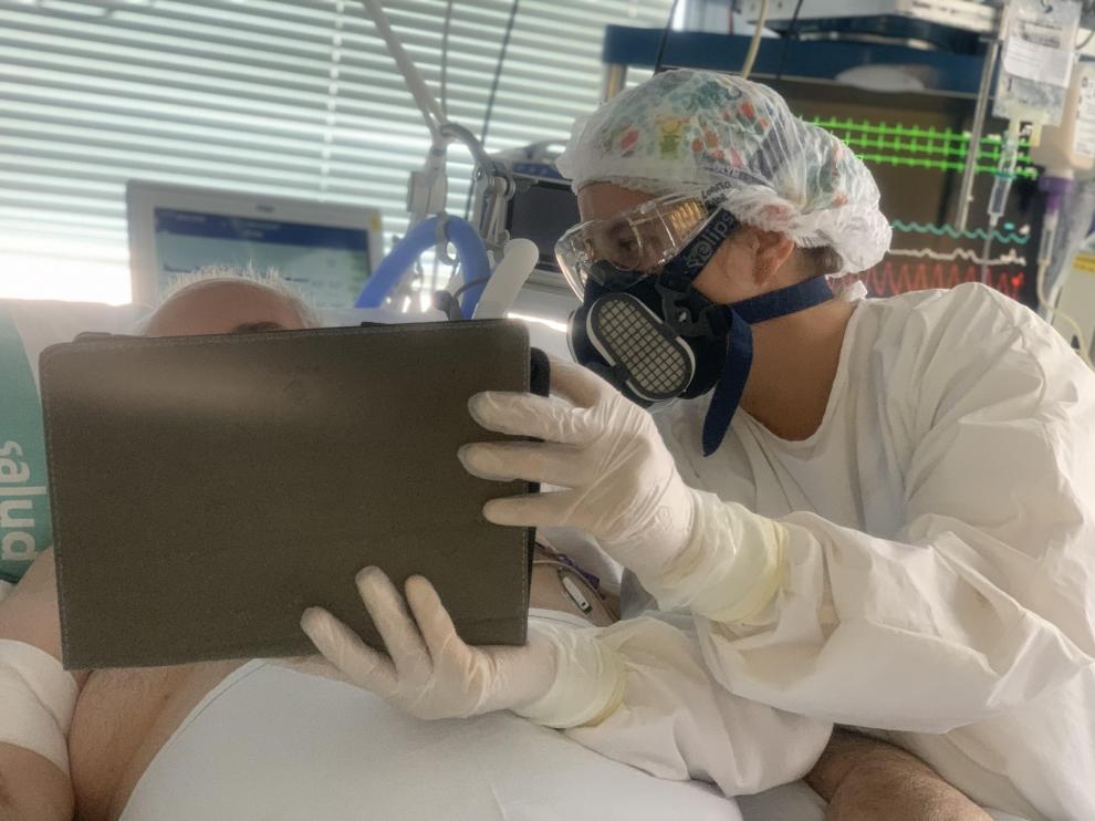 Una enfermera de la UCI sostiene la tablet mientras el paciente habla con sus familiares.