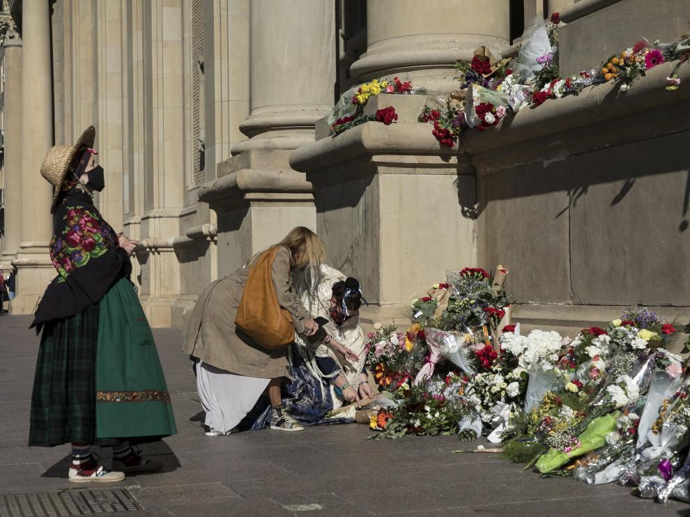 Algunas personas se acercaron ayer al conjunto escultórico de la fachada del Pilar a depositar ramos de flores.