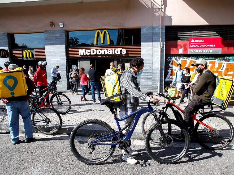 Varias personas esperan para coger comida para llevar en Barcelona, tras el cierre de bares y restaurantes.