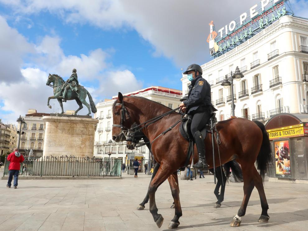Dos agentes de policía nacional montados a caballo vigilan las inmediaciones de la Puerta del Sol un día antes del término del estado de alarma, en Madrid