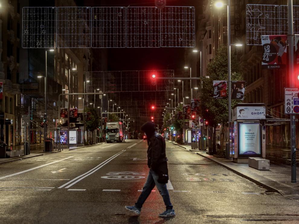 Un joven cruza una calle del centro de Madrid durante la primera noche de toque de queda en la capital.