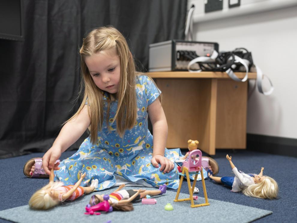 Una niña juega con varias muñecas.