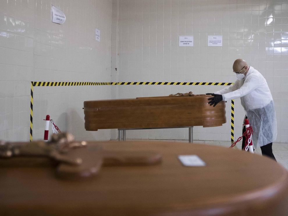 El empleado de una funeraria coloca un féretro con un fallecido por covid en el tanatorio de Torrero de Zaragoza.