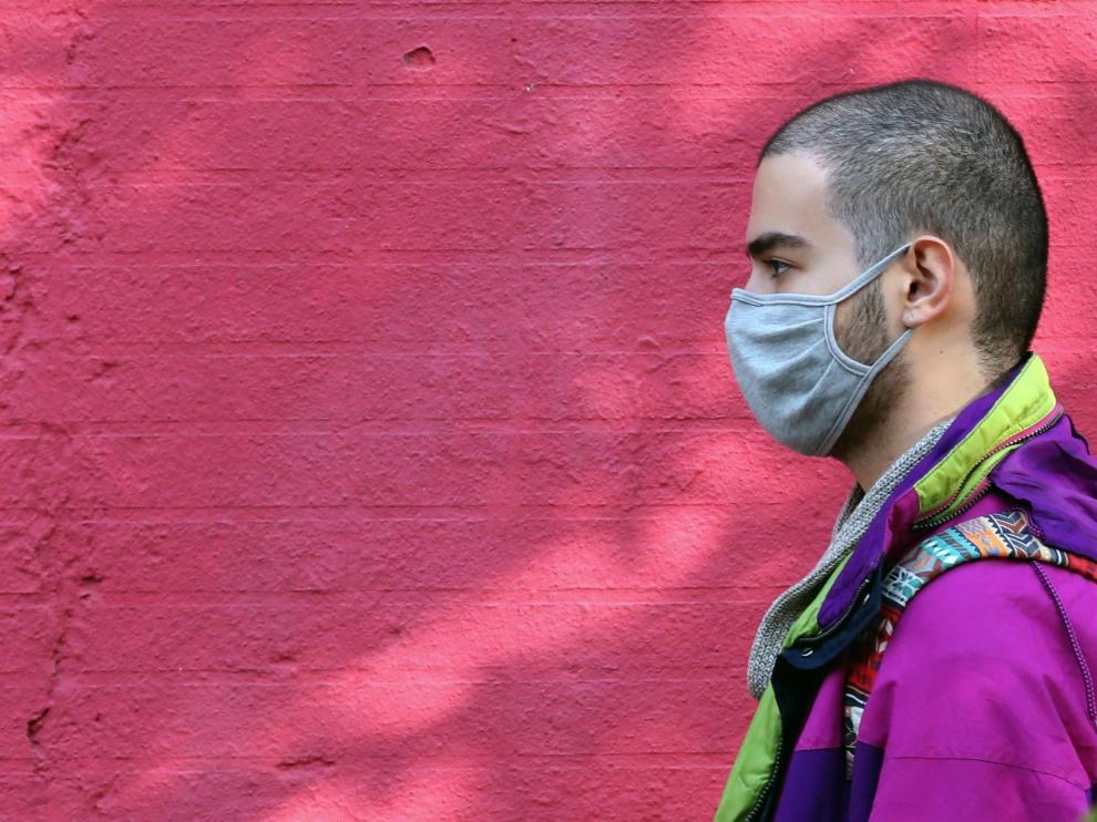 Un joven camina por la calle con mascarilla