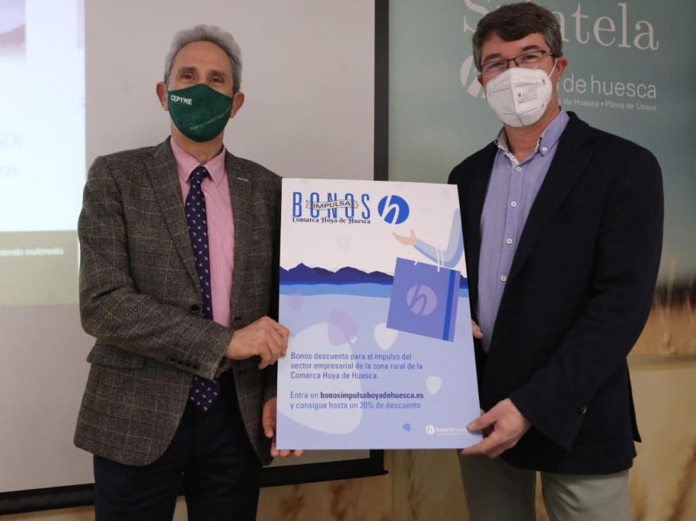 Salvador Cored, director general de la CEOS, y Sergio Moreu, consejero de Desarrollo de la Comarca Hoya de Huesca, con el cartel de la campaña.