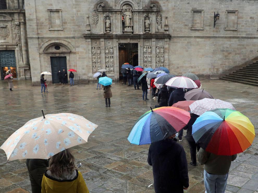 Varias personas aguardan bajo la lluvia para entrar a la catedral de Santiago por la Puerta Santa