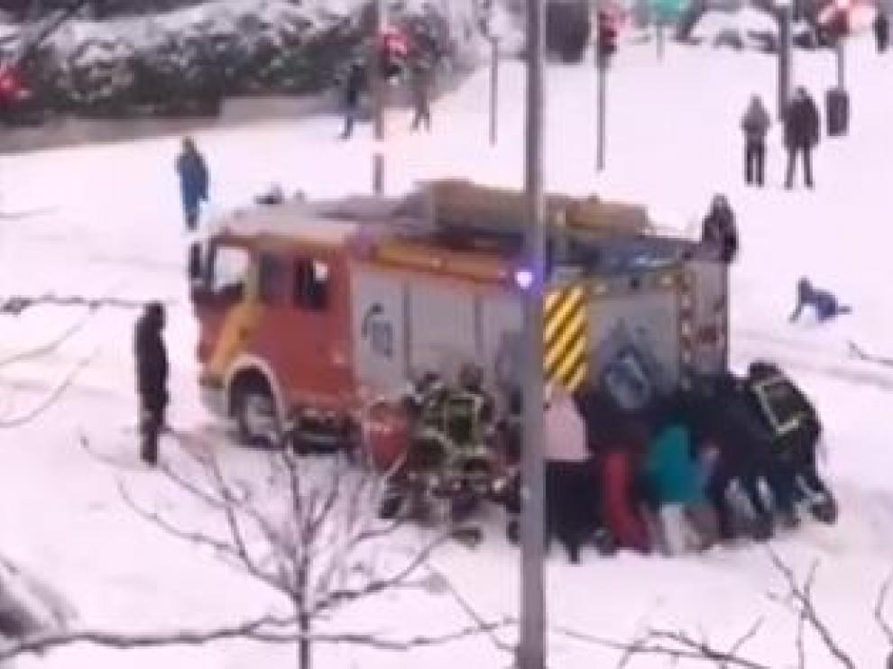 Un grupo de ciudadanos empujan un camión de los Bomberos, atrapado por la nieve en una calle de Madrid.