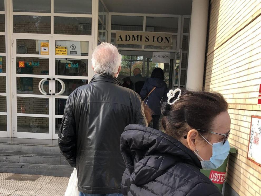 Varias personas hacen fila a las puertas de un centro de salud en Zaragoza.