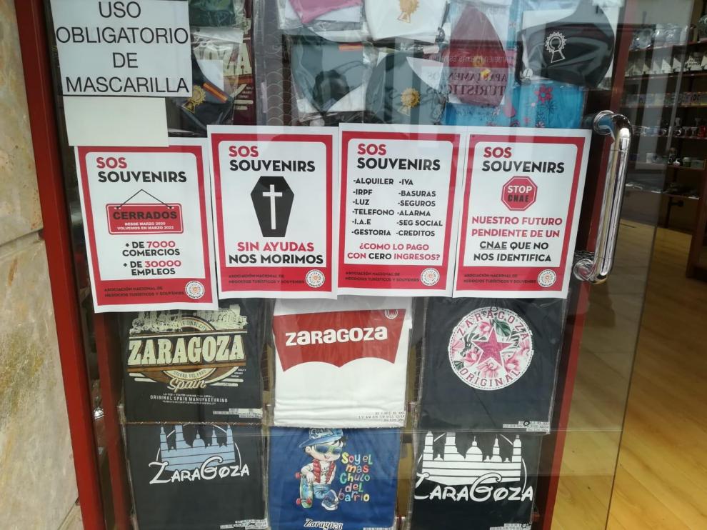 Carteles denunciando la difícil situación económica que atraviesa el sector, en el escaparate de una tienda de Zaragoza.
