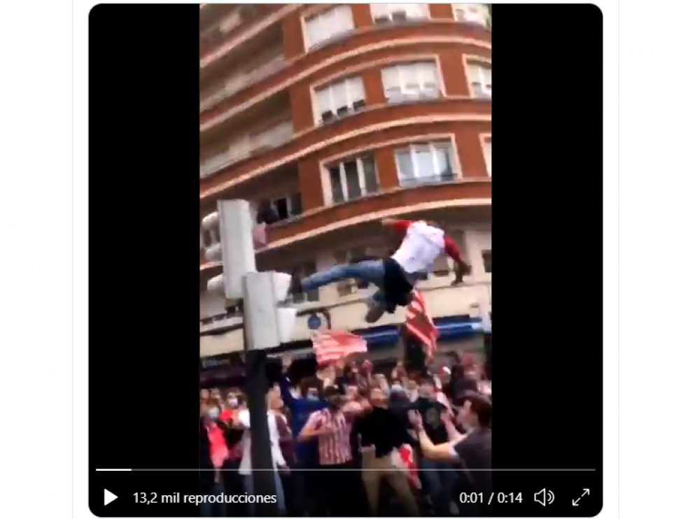Imagen de un aficionado del Athletic saltando desde un semáforo entre la multitud, en Bilbao.