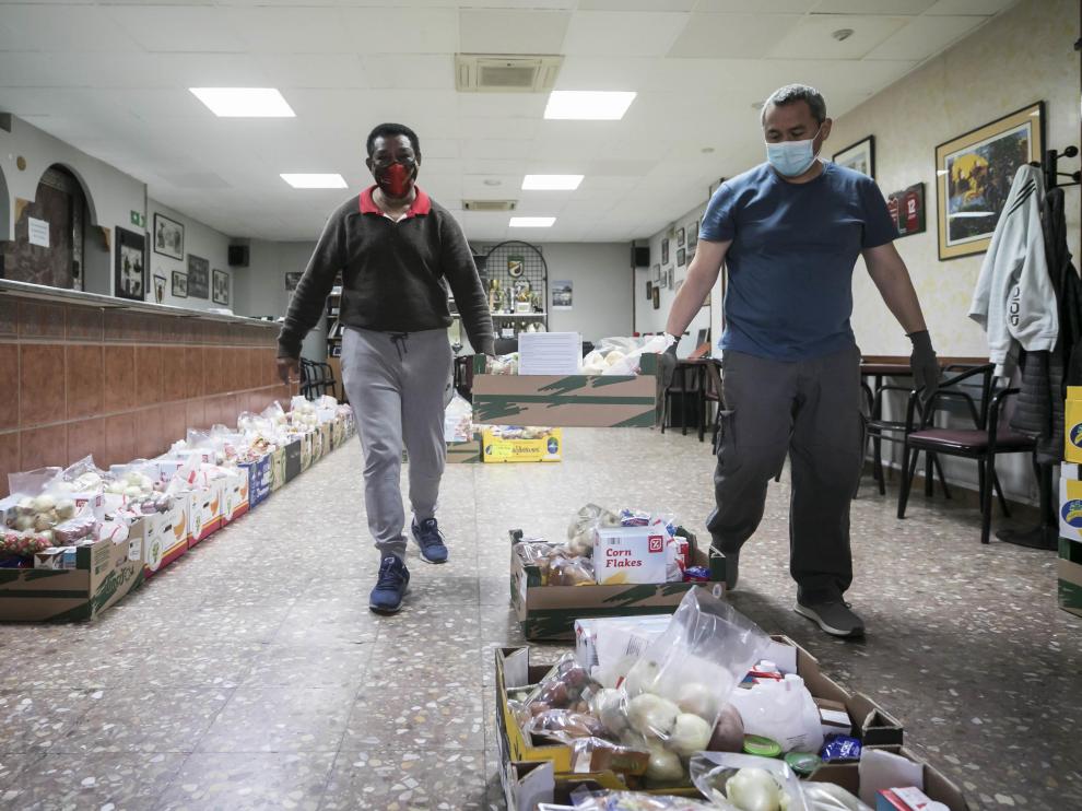 Dos voluntarios mueven un lote de comida para el reparto de la asociación Civitas de Las Fuentes.