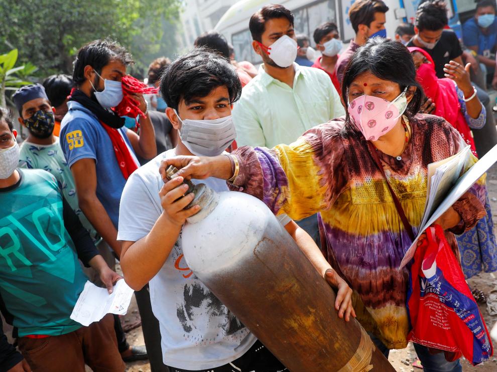Una mujer y su hijo portan una bombona de oxígeno para recargarla en Nueva Delhi.