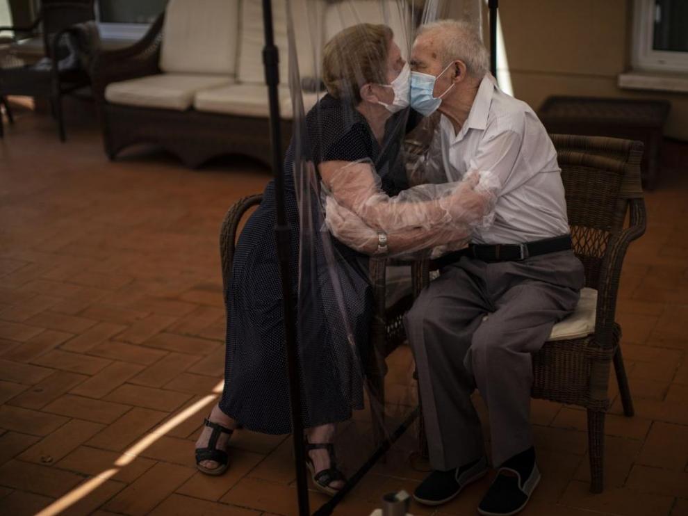 Agustina Cañamero, de 81 años, abraza y besa a su marido, Pascual Pérez, de 84, a través de un plástico en una residencia de Barcelona, el 22 de junio de 2020