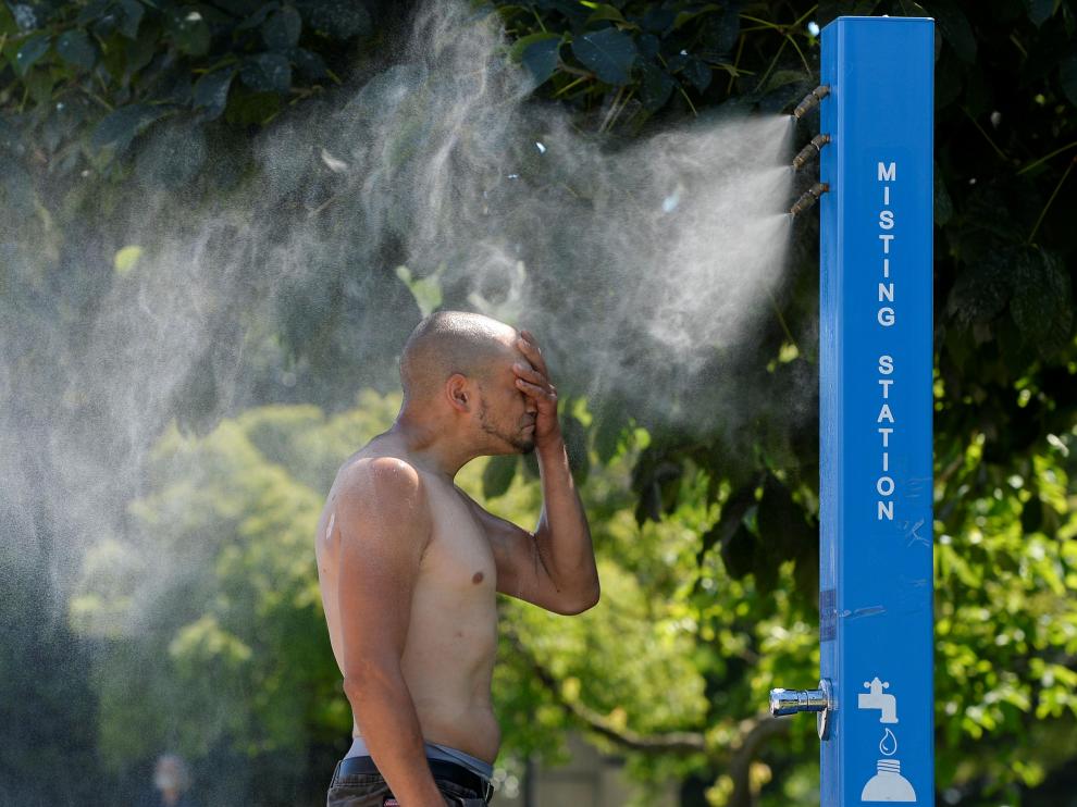 Un hombre se refresca en un nebulizador colocado en una calle de Vancouver