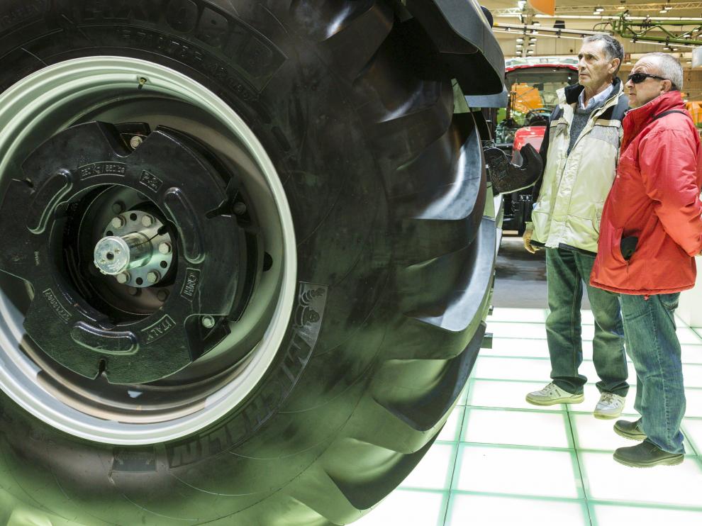 Dos hombres contemplan una enrome máquina agrícola durante la celebración de la Feria Internacional de Maquinaría Agrícola que se celebra en Zaragoza.